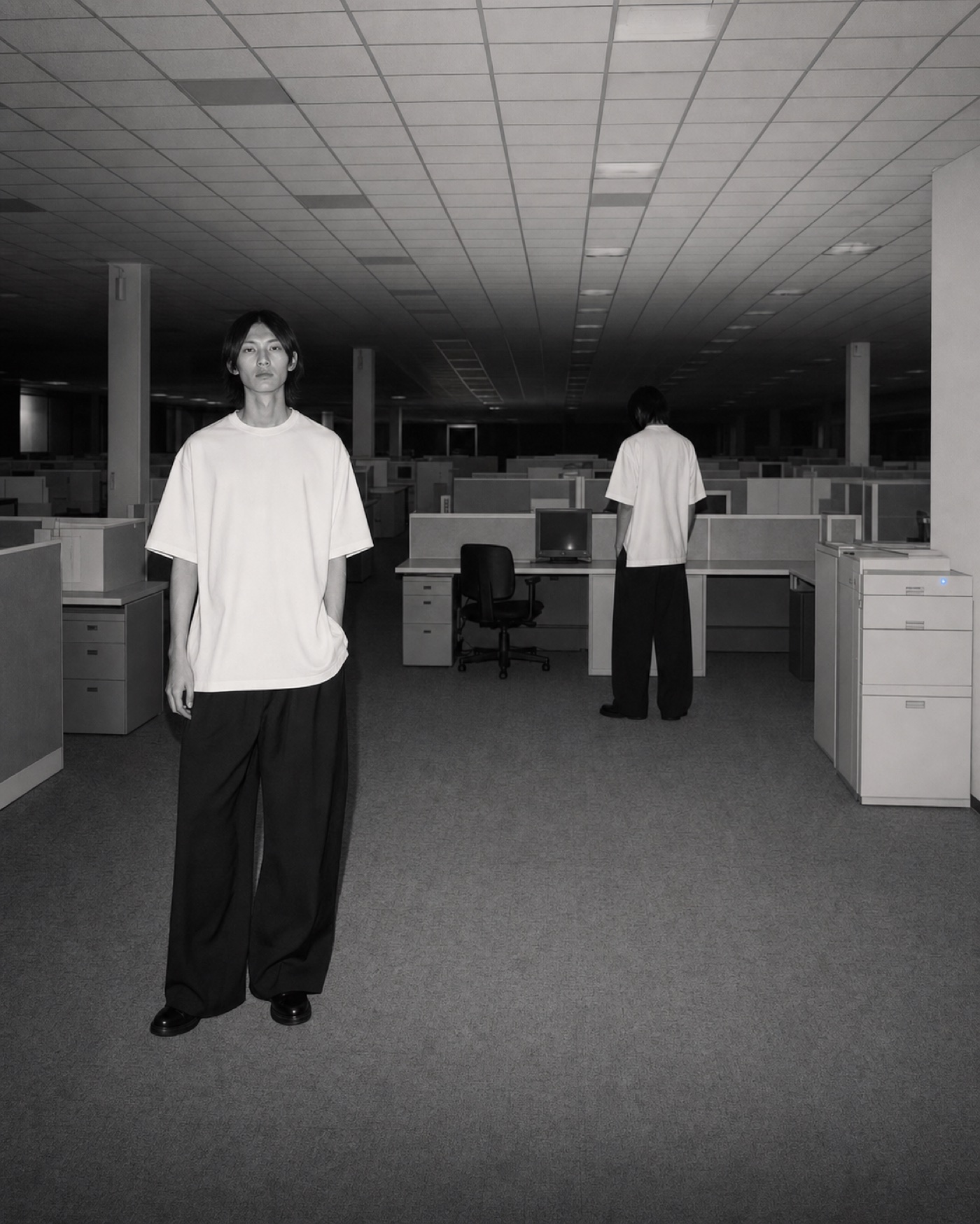 Two models in oversized white T-shirts inside an empty office